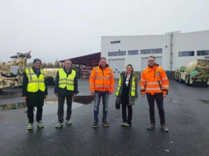Small group of people in front of a building wearing safety vests